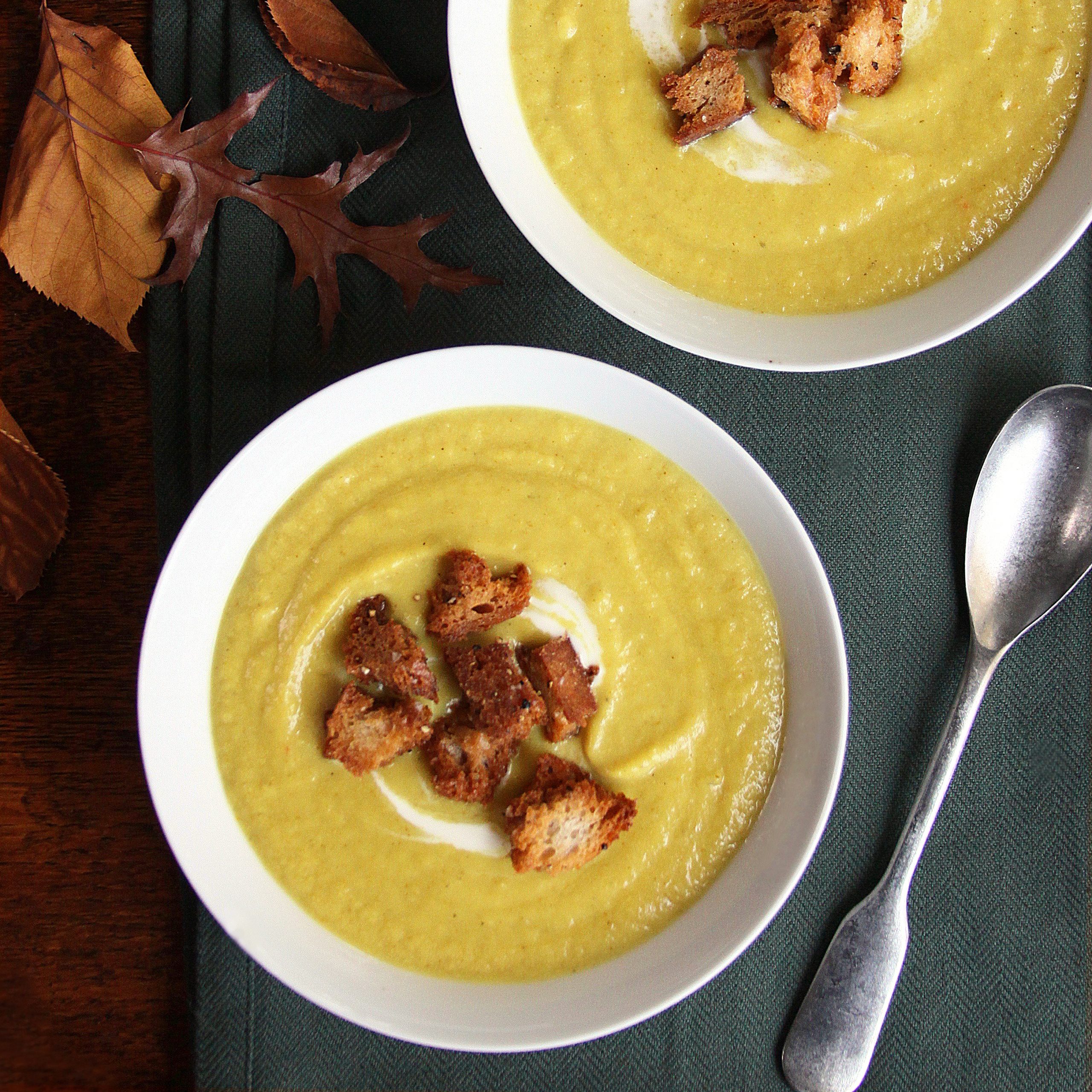 Two bowls of curried parsnip soup with croûtons